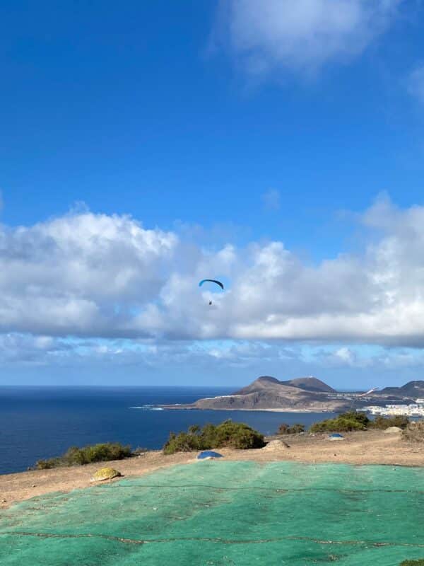 Person paragliding over the beach.
