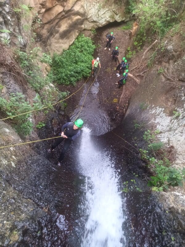 Person climbing next to a waterfall.