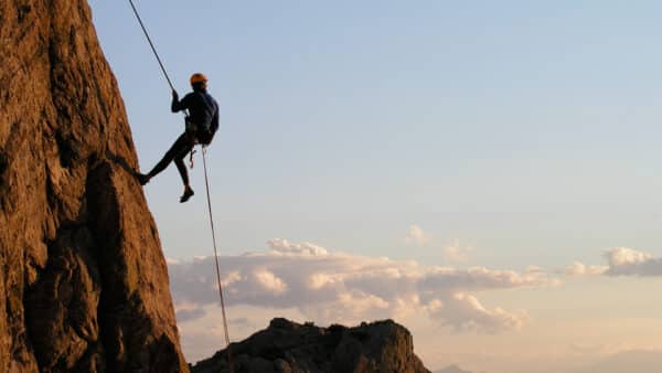 Man climbing with a rope.