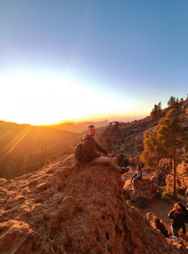 Man sitting on a mountain at sunset.