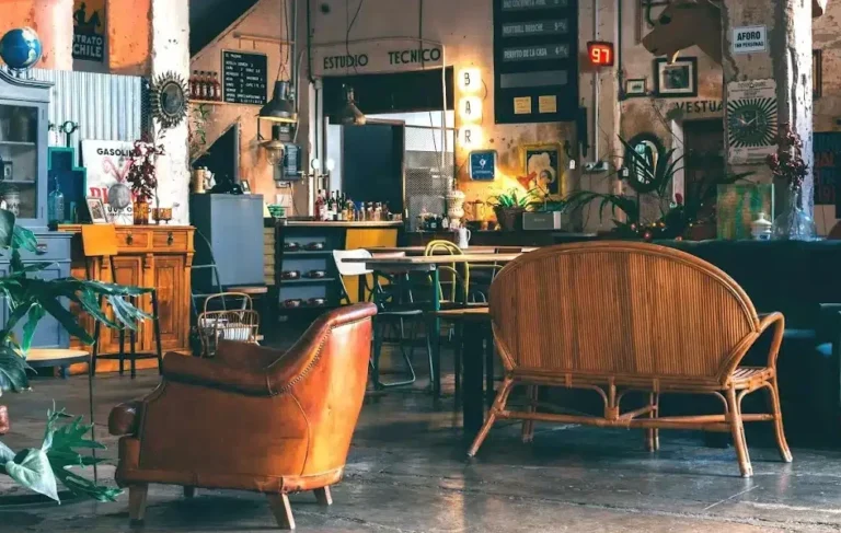 A spacious coworking space filled with various furniture pieces and numerous indoor plants, creating a vibrant atmosphere.